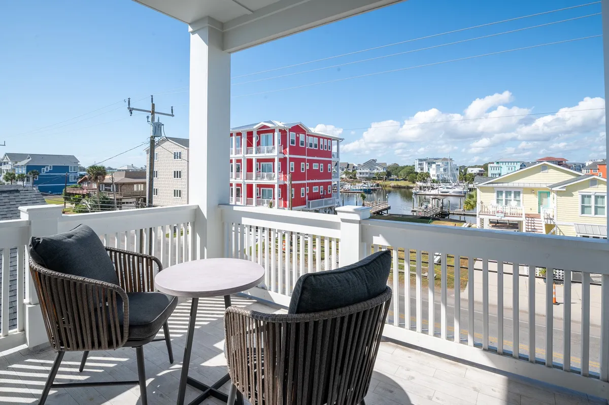 An outdoor seating area overlooking the water, with comfortable chairs and colorful buildings in the background. The porch is ideal for soaking up canal views and enjoying coffee or conversations as the sun rises or sets.
