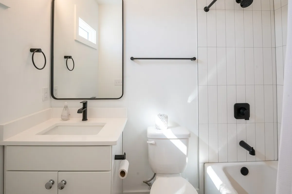 A bright, modern bathroom with a large vanity, expansive mirror, and glass-enclosed shower. Minimalist fixtures and serene lighting provide a refreshing space for morning and evening routines.