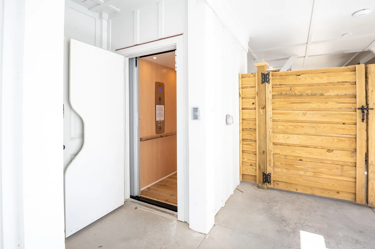 A view of the home's elevator entrance framed by a wooden gate, set within a welcoming interior. The space hints at easy access between floors for all ages, enhancing the sense of comfort and inclusivity.