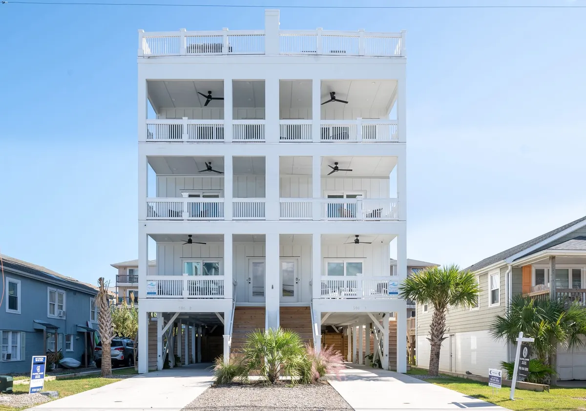 The image shows a striking four-story single-family house just steps from Carolina Beach, framed by swaying palm trees. Multiple balconies with stylish railings invite outdoor lounging, with glimpses of cheerful family gatherings and sunset views from the upper levels. The setting feels spacious, bright, and perfect for group relaxation, with plenty of opportunities for morning coffee, evening barbecues, and stargazing.