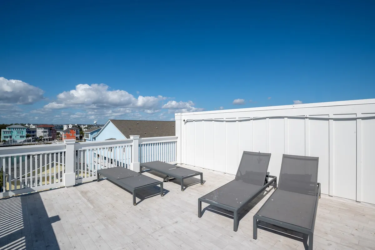 This image showcases a serene rooftop deck with lounge chairs positioned to take in expansive views under a blue sky. The open space invites relaxation and social gatherings while highlighting the elevated perspective over the surrounding area.