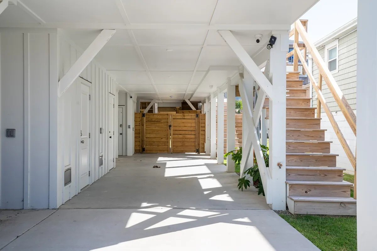 An exterior view of a staircase, sturdy wooden fencing, and supportive beams, leading down to a welcoming yard. The area is set up for casual gatherings and offers ample room for children or pets to play safely within the fenced boundaries.